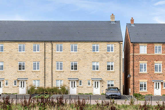 A row of houses with cars parked in front.