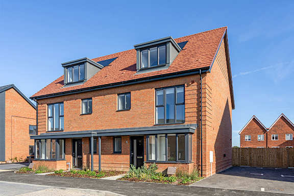 A red brick house with a black roof and a blue awning.
