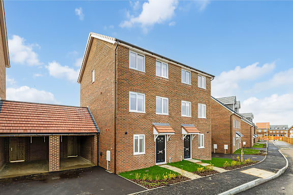 A row of red brick houses with green lawns in front.