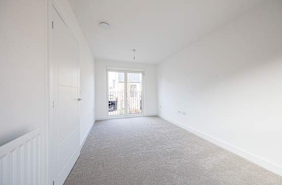 A spacious room with white walls and a carpeted floor.
