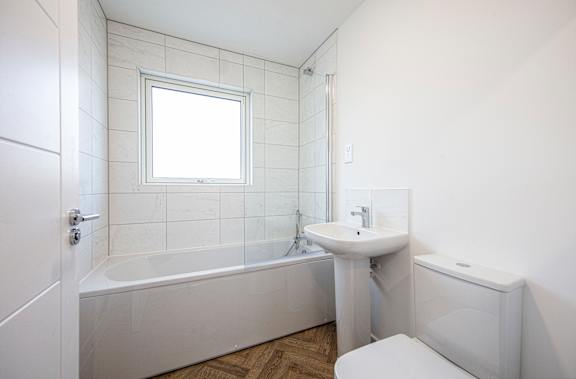A white bathroom with a tub, sink, and toilet.