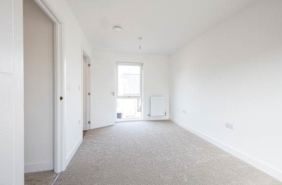 A large, empty room with white walls and carpeted floor.