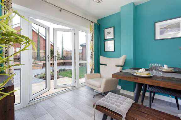 A dining room with a table set for two and a view of the backyard.