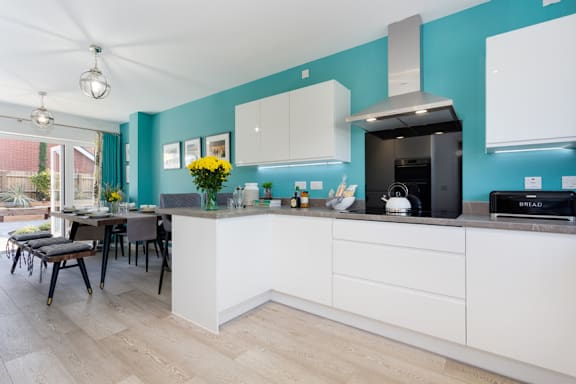 A kitchen with white cabinets and a blue wall.