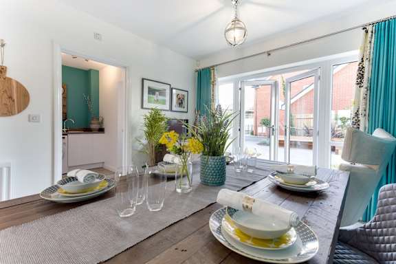 A dining room with a table set for two and a view of the backyard.