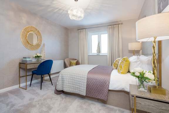 A bedroom with a bed, desk, chair, and a window.