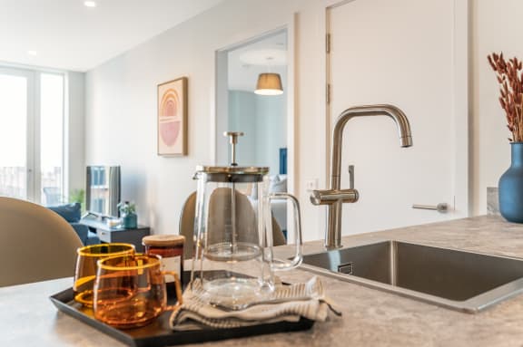 a kitchen counter with a sink and a faucet and a tray of glasses