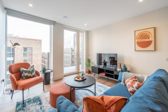 a living room with a blue couch and orange chairs and a television