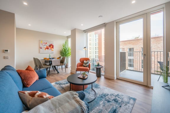 a living room with a blue couch and a table and a balcony