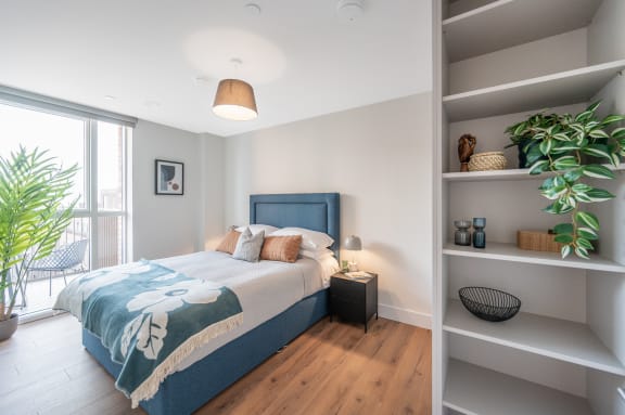 a bedroom with a blue and white bed and a book shelf