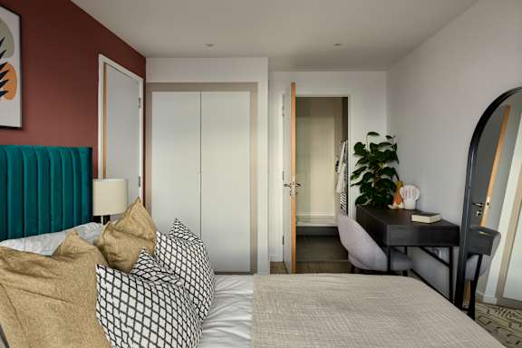 A bedroom with a bed, a desk, and a mirror.