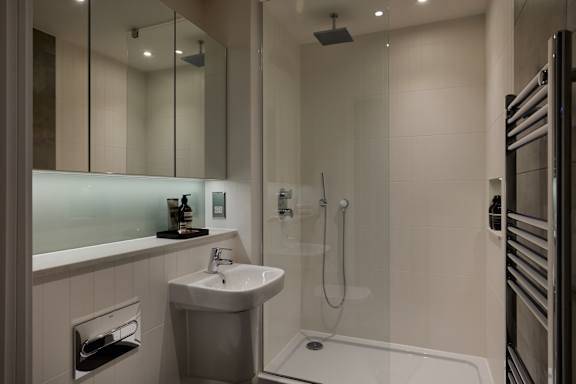 A modern bathroom with a white sink and a walk-in shower.