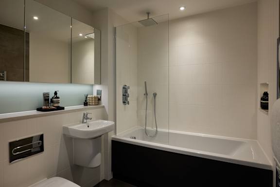 A modern bathroom with a white sink and a black and white bathtub.