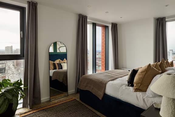 A bedroom with a large bed and a view of the city.