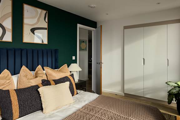 A bedroom with a bed, pillows, and a plant.