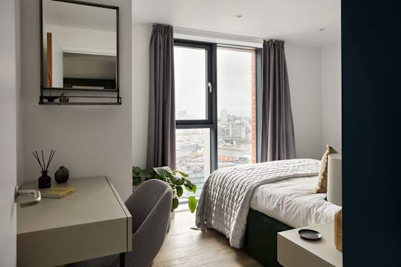 A bedroom with a bed, desk, and chair.
