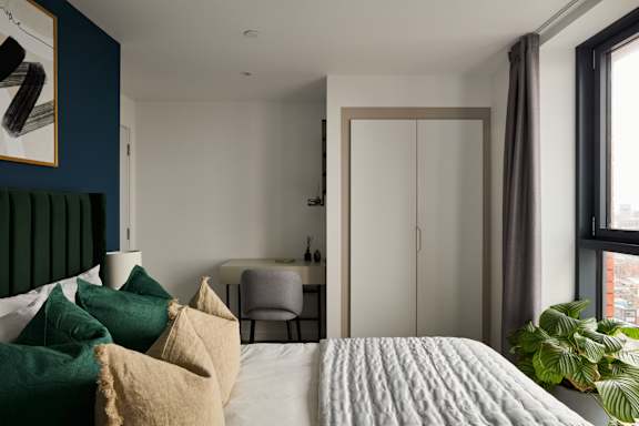 A bedroom with a bed, chair, and a painting on the wall.