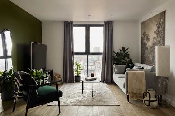 A living room with a green chair and a large window.