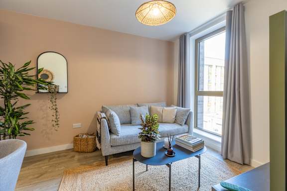A living room with a grey couch, a round table, and a plant.