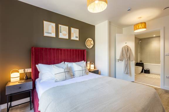 A bedroom with a red headboard and a white bed.