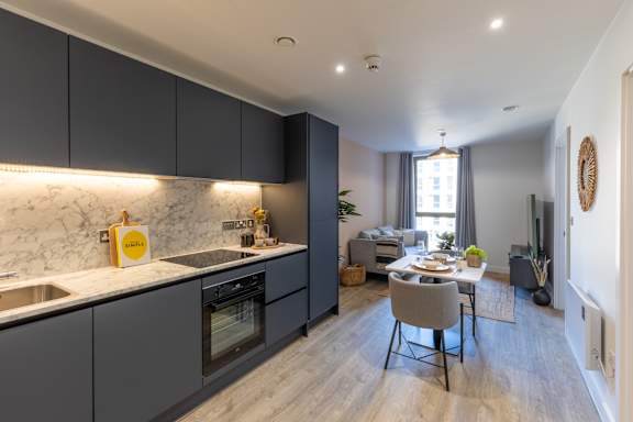 A modern kitchen with a marble backsplash and dark grey cabinets.