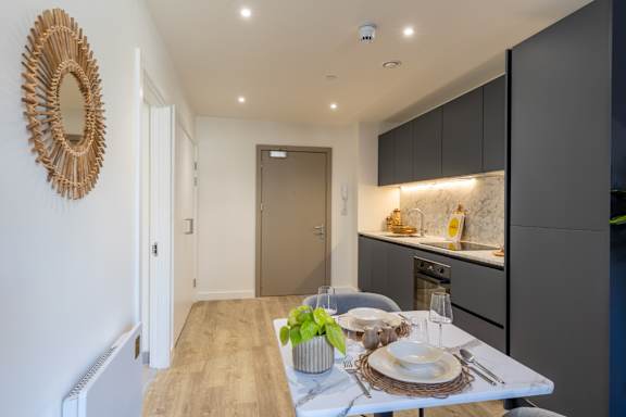 A modern kitchen with a wooden table set for a meal.