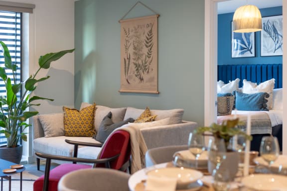 a living room with couches and tables and a bed in the background
