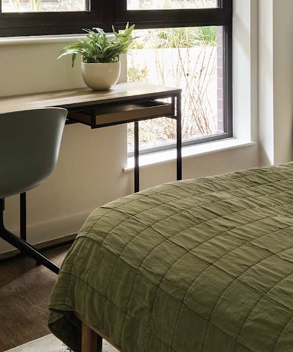 a bedroom with a large window and a bed with a blanket