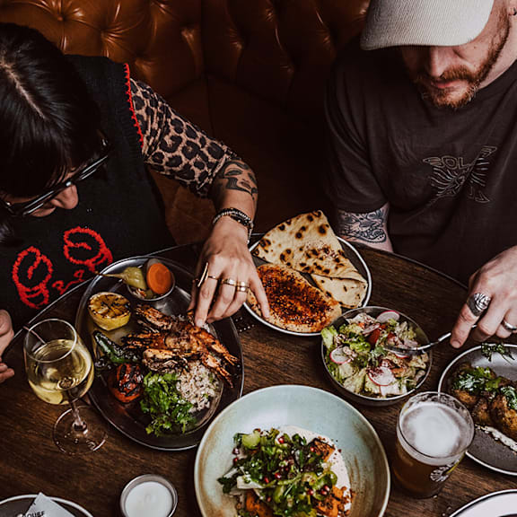 A man and woman are sitting at a table with plates of food in front of them.