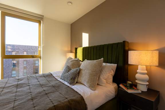 A bedroom with a large bed and a window overlooking a cityscape.