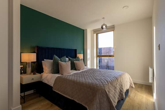 A bedroom with a bed, nightstand, and lamp.