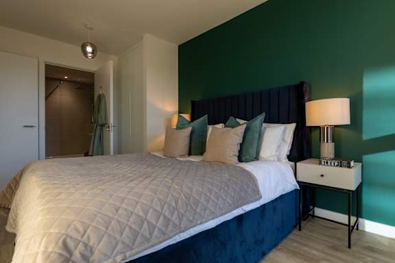 A bedroom with a large bed and a nightstand with a lamp.