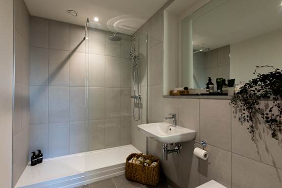 A bathroom with a white sink and a glass shower stall.