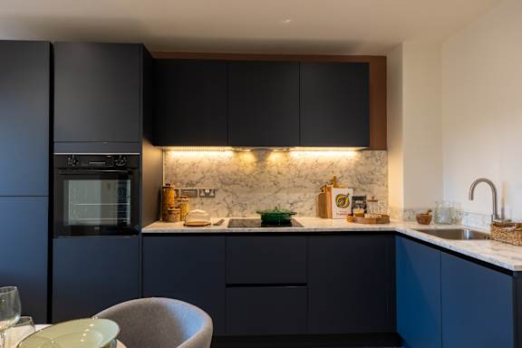 A modern kitchen with dark cabinets and a marble backsplash.