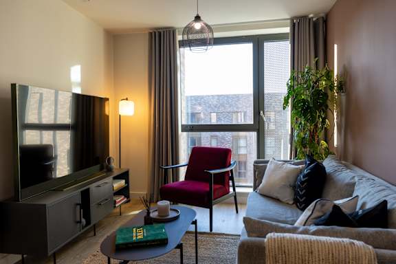 A living room with a red chair and a grey couch.