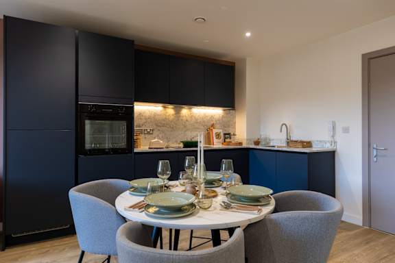 A modern kitchen with a dining table set for two.