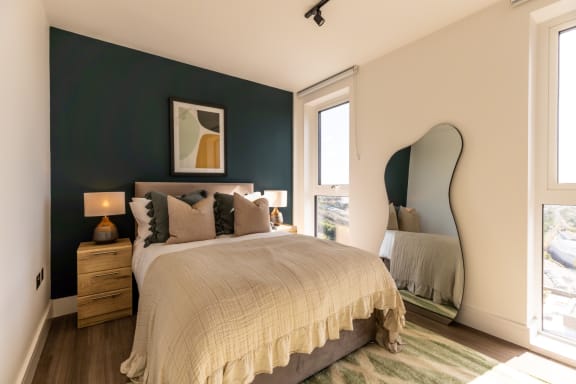 a bedroom with a bed and a mirror and a green accent wall