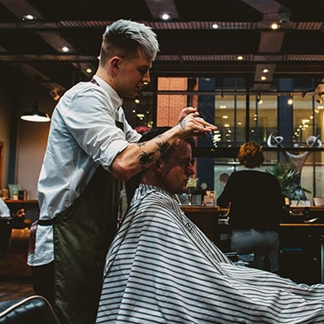 a man cutting another mans hair in a barber shop