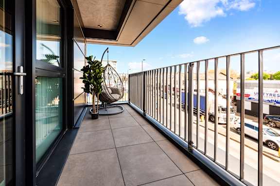 a balcony with a potted plant and a view of the street