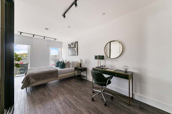 a bedroom with a bed and a desk and a large window