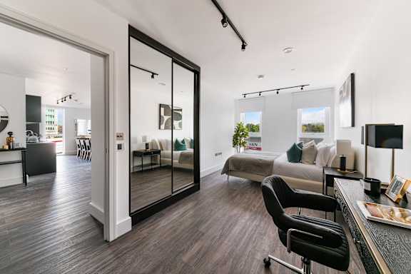 a living room with a bed and a desk and a mirror