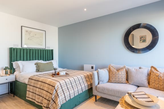 a bedroom with a bed and a couch and a mirror