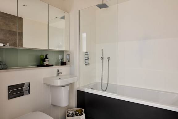 A modern bathroom with a white sink and a glass shower stall.