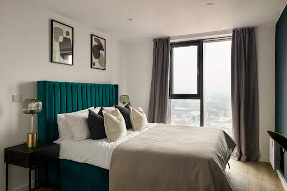 A bedroom with a large bed and a view of the city.