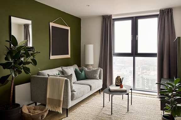 A living room with a grey couch, a small table, and a large window.