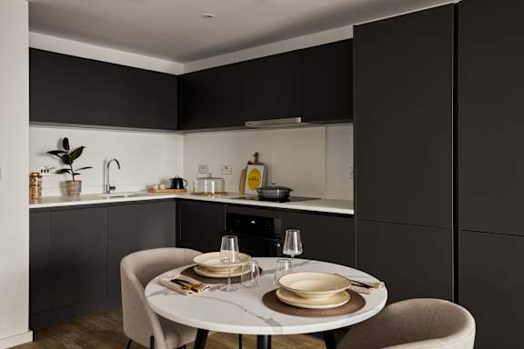 A modern kitchen with a dining table set for two.