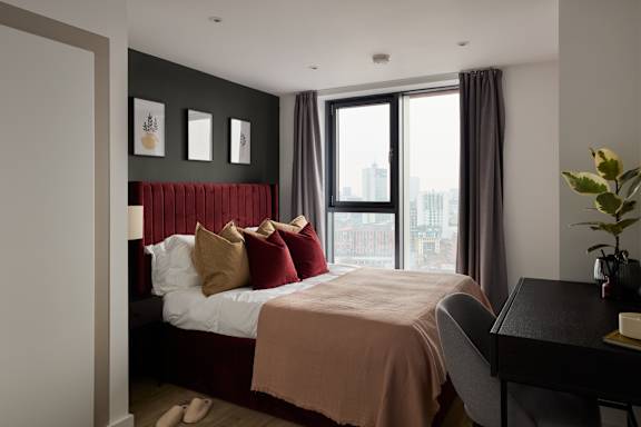 A bedroom with a large bed and a desk.