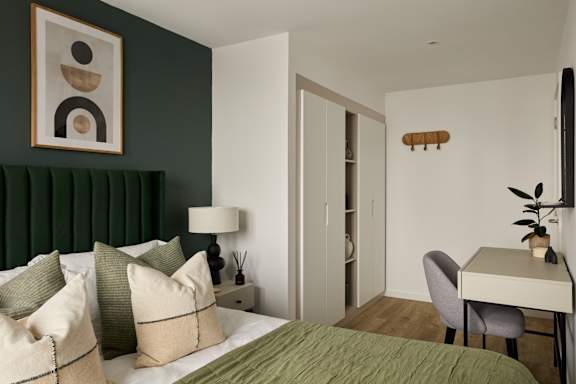 A bedroom with a bed, a desk, and a chair.