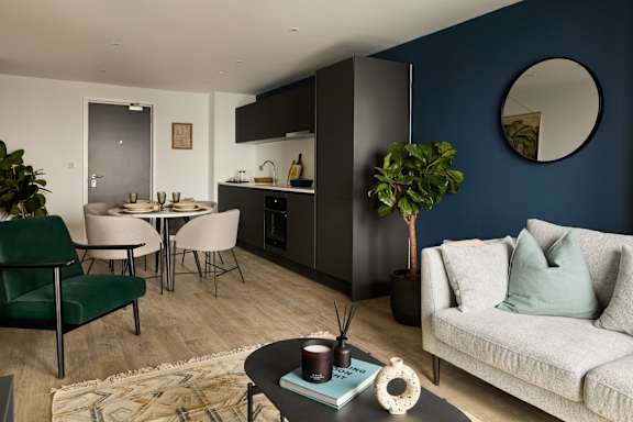 A modern living room with a dining area and a kitchen in the background.