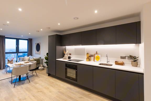 A modern kitchen with dark brown cabinets and a wooden floor.